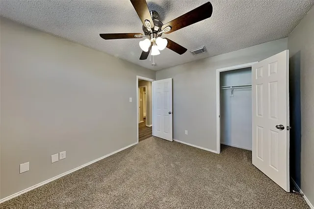 an empty room with closet and a ceiling fan