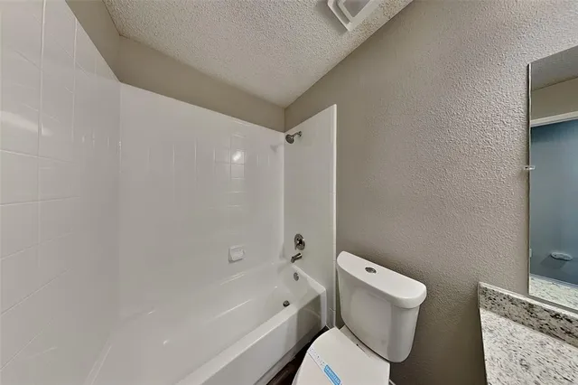 a white toilet sitting next to a bath tub