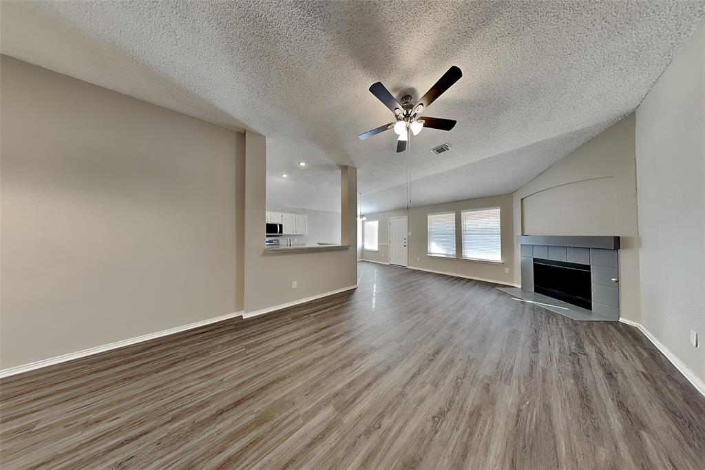 3304 Athens Drive Corinth, TX 76210 - Photo 4 of 22 a view of an empty room with a fireplace and wooden floor