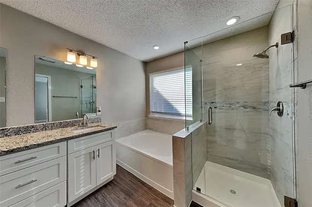 a bathroom with a granite countertop sink a mirror and a bathtub