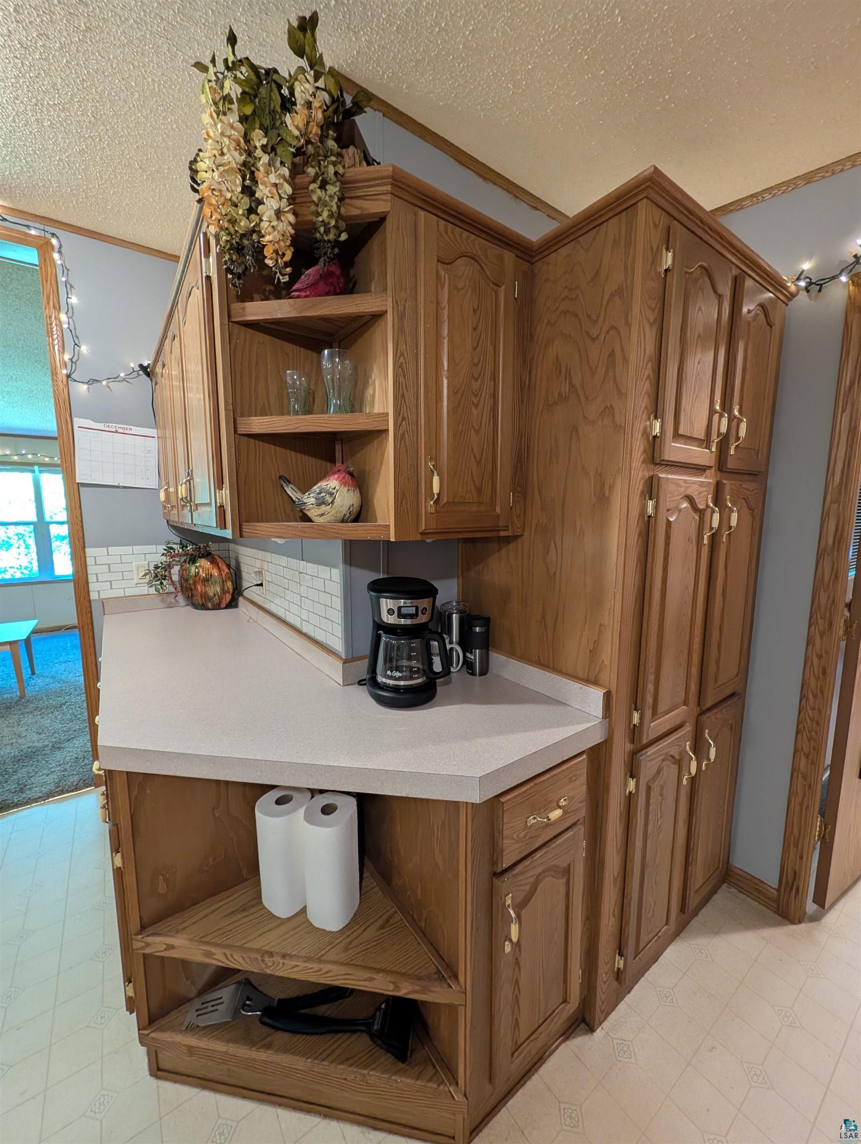 3945 Maple Street Kettle River, MN 55757 - Photo 9 of 41 Kitchen featuring light wood cabinetry, pale countertop, subway tile backsplash, and corner shelving
