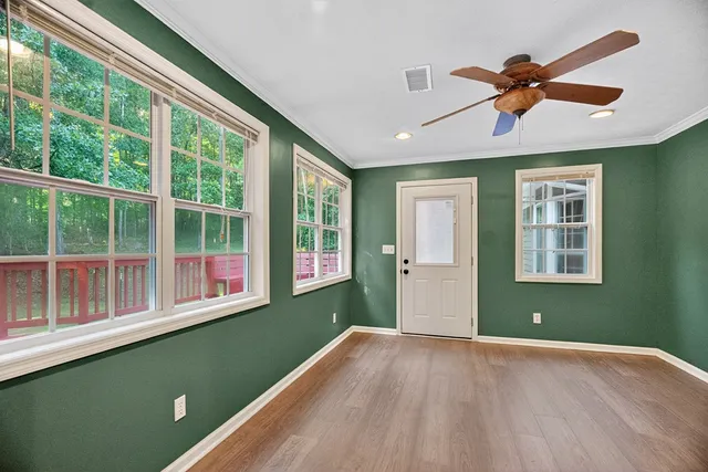 a view of a livingroom with a ceiling fan & windows
