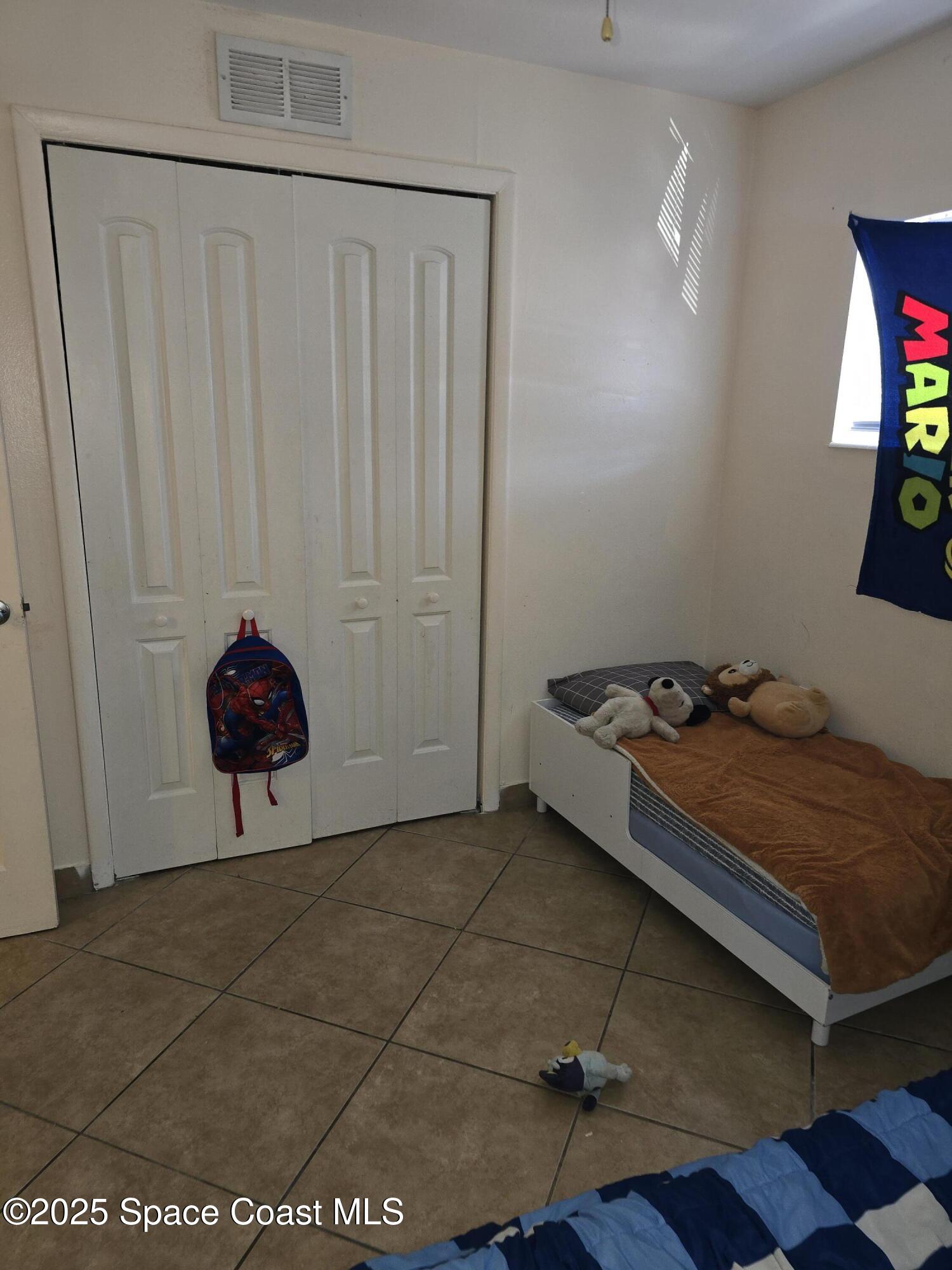 180 Minna Lane, Unit 402 Merritt Island, FL 32953 - Photo 7 of 10 a bedroom with a bed and a chandelier