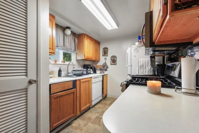 a large white kitchen with a sink a stove a chimney a couch and a window