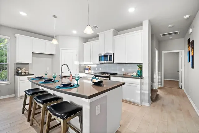 a kitchen with a sink a stove a refrigerator and white cabinets with wooden floor