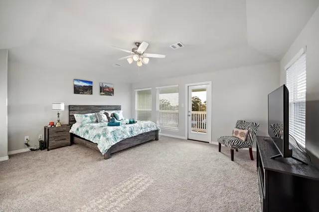 a spacious bedroom with a bed a couch and a flat tv screen on the dresser