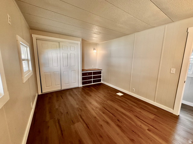 158 Cushing Way Layton, UT 84041 - Photo 8 of 14 Spacious room featuring wood-finish flooring, light-toned vertical paneling, and a built-in storage unit with dark wood-finish drawers