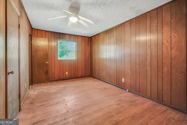 an empty room with windows and a chandelier fan