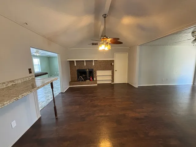 an empty room with kitchen and fireplace