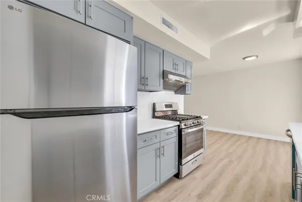 a kitchen with stainless steel appliances a refrigerator a stove a sink and white cabinets