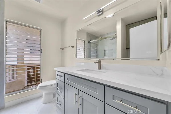 a bathroom with a granite countertop sink a toilet and a mirror