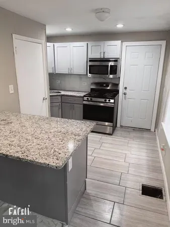 a kitchen with kitchen island granite countertop a stove and a refrigerator