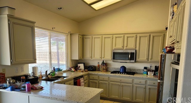 12915 Lompoc Road Apple Valley, CA 92308 - Photo 8 of 23 a kitchen with stainless steel appliances a sink a stove a refrigerator cabinets and a window