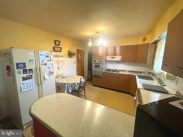 2146 Fairview Avenue Reading, PA 19606 - Photo 16 of 25 a large white kitchen with a refrigerator a sink dishwasher a stove and a dining table with wooden floor
