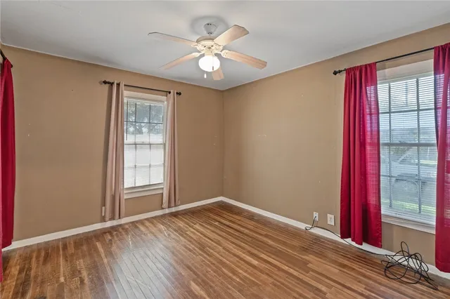 a view of an empty room with a window and wooden floor