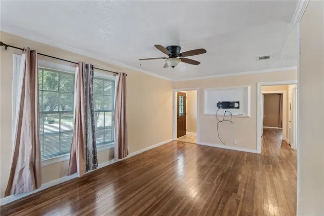 a view of empty room with wooden floor and fan