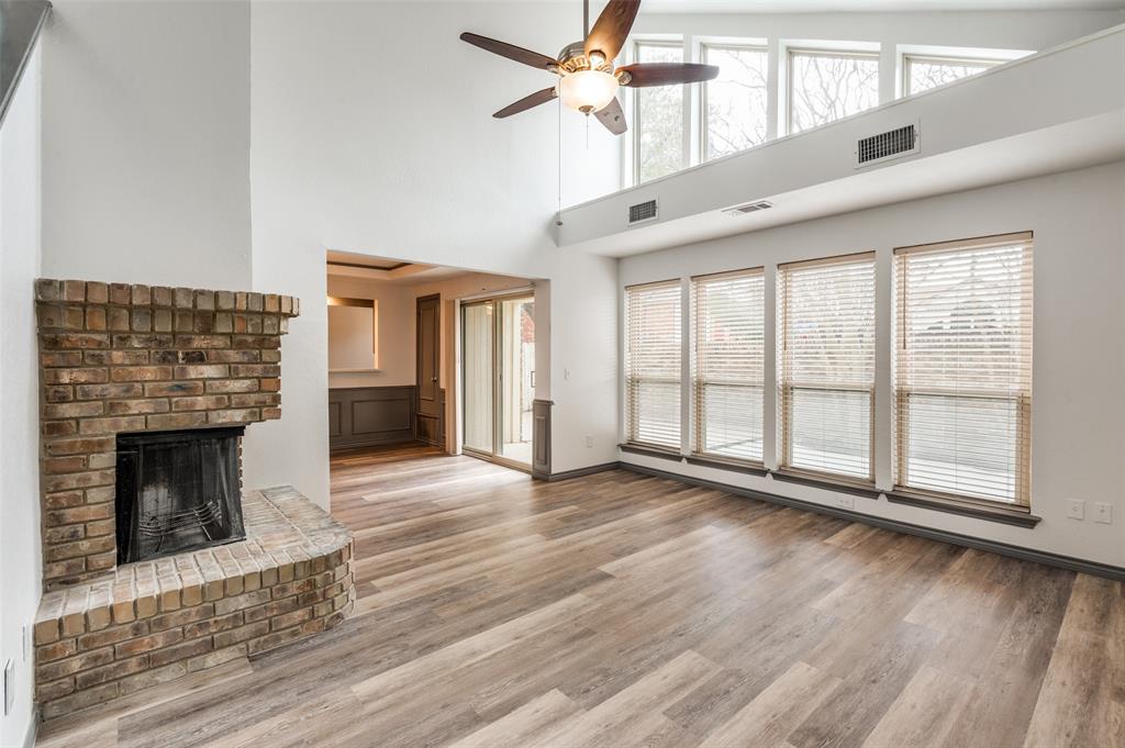 a view of an empty room with wooden floor fireplace and a window