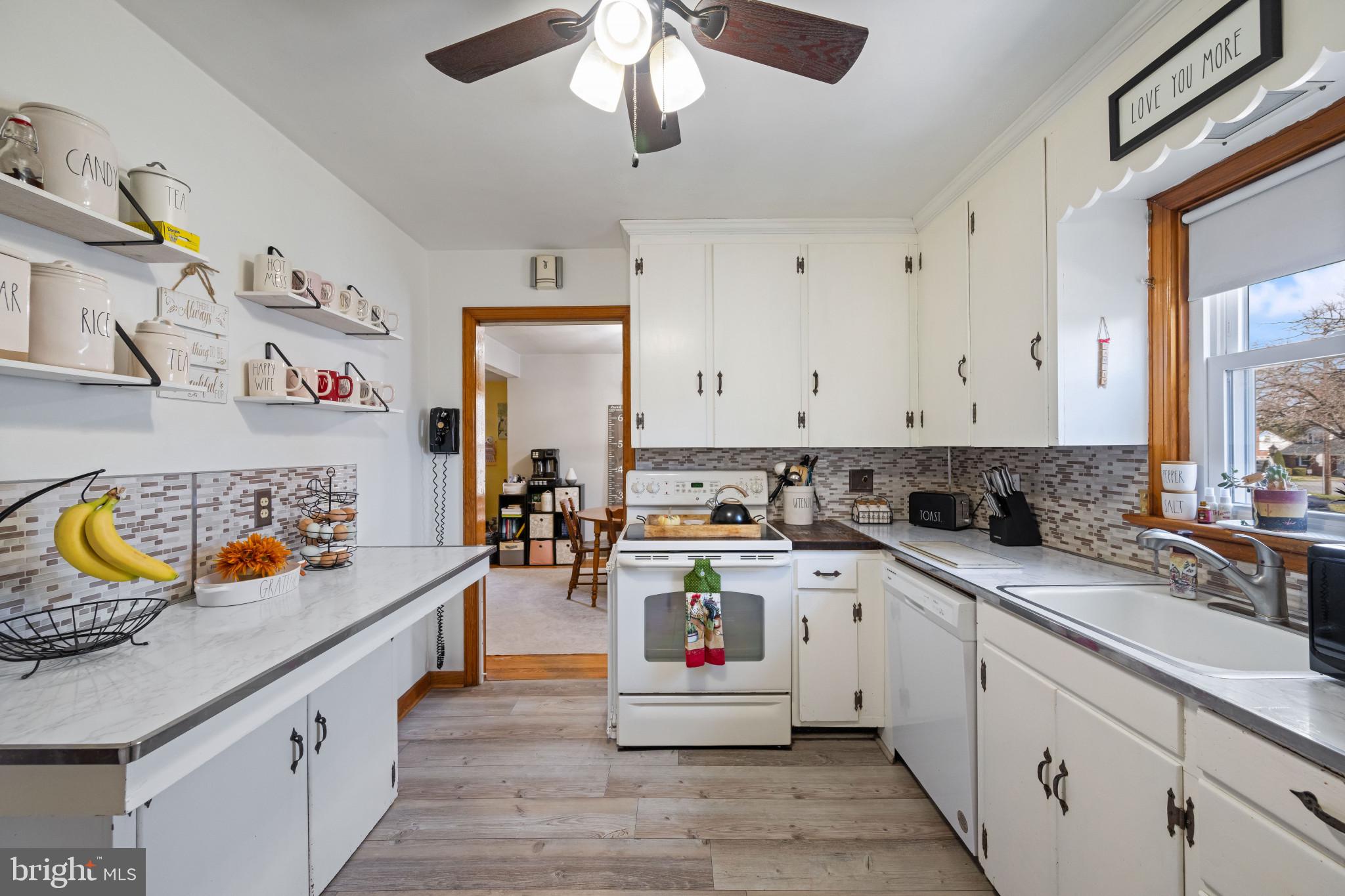 4207 Ralph Avenue Hampstead, MD 21074 - Photo 9 of 33 a kitchen with a sink dishwasher and white cabinets with wooden floor