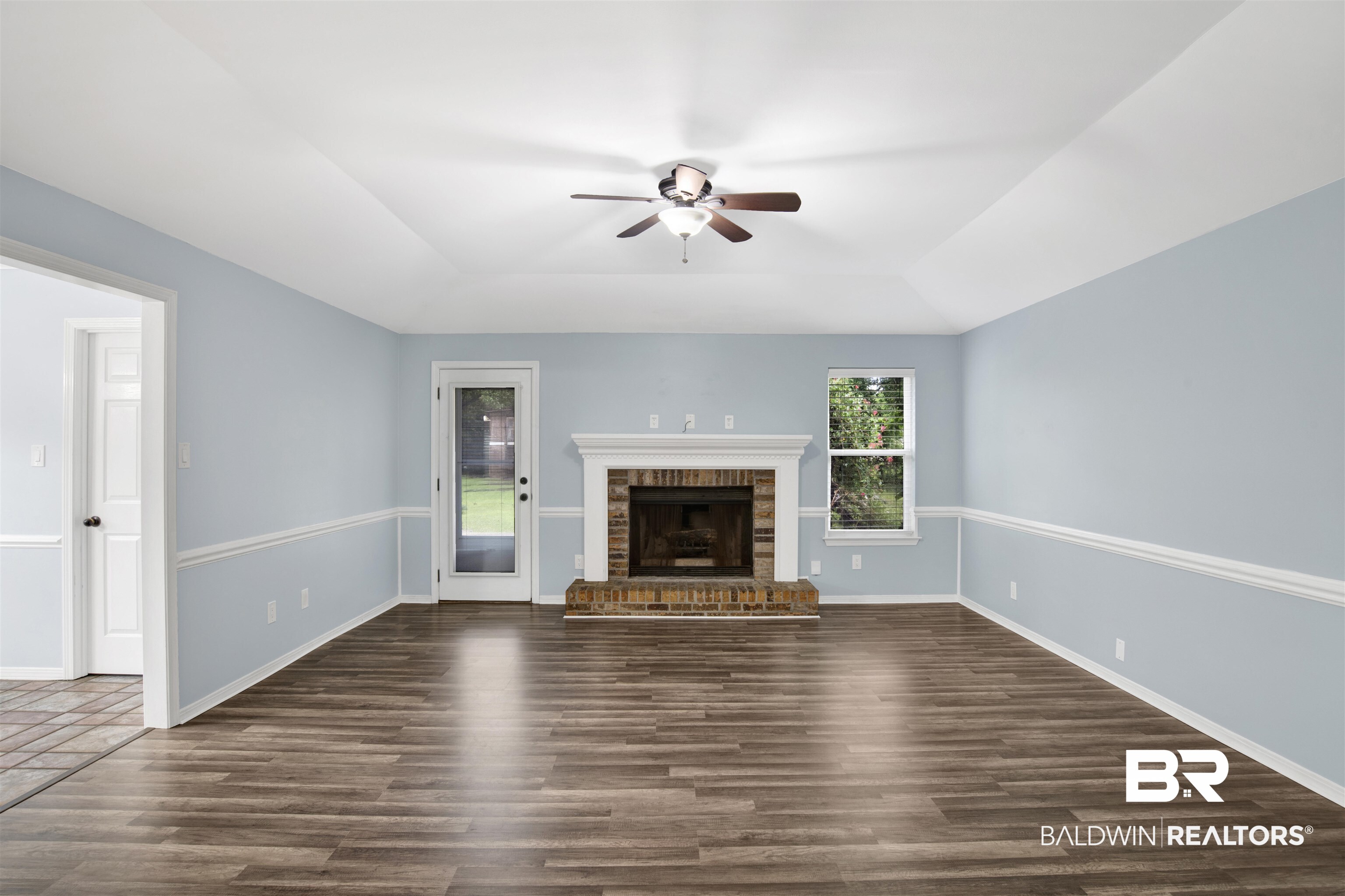 3011 Olde Gate Road Mobile, AL 36695 - Photo 10 of 35 Unfurnished living room featuring a tray ceiling, ceiling fan, dark wood-type flooring, and a fireplace