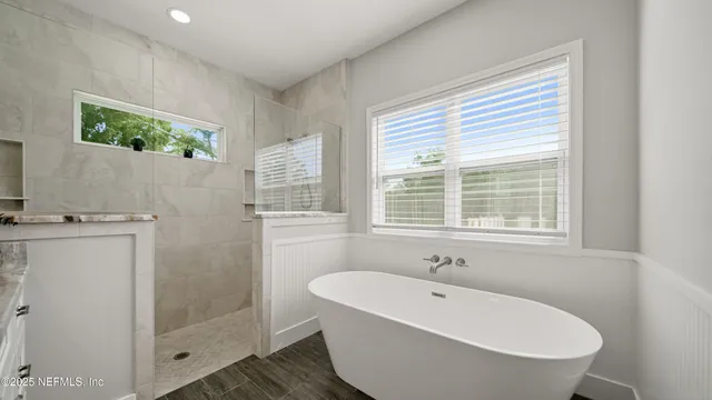 a bathroom with a granite countertop tub sink and mirror