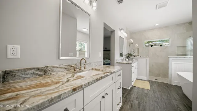 a bathroom with a granite countertop sink mirror bathtub and window