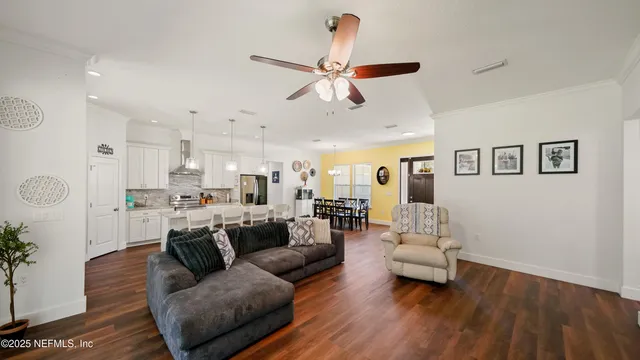a living room with furniture kitchen view and a wooden floor