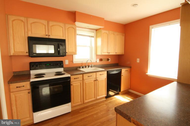 703 Dorchester Road Baltimore, MD 21229 - Photo 15 of 27 a kitchen with stainless steel appliances granite countertop a stove a sink and a microwave