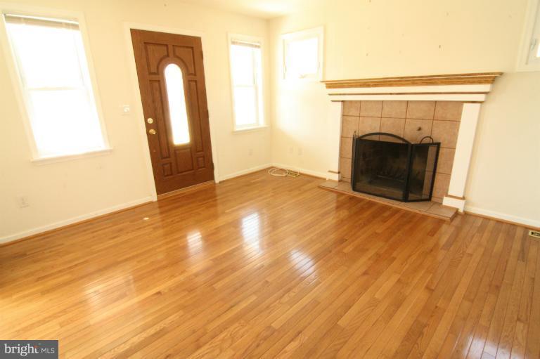 703 Dorchester Road Baltimore, MD 21229 - Photo 17 of 27 a view of empty room with wooden floor and fireplace