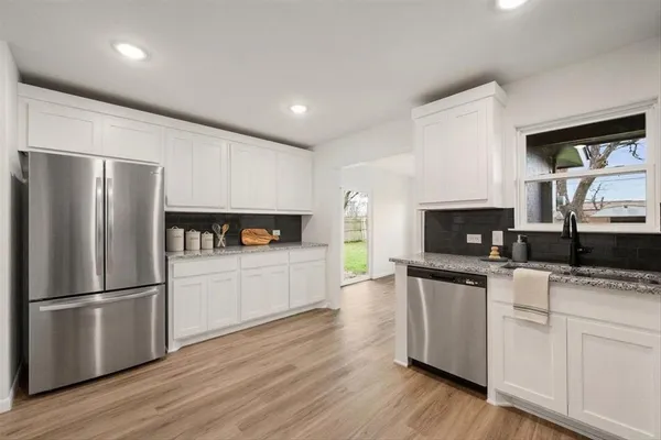 a kitchen with granite countertop a refrigerator stove top oven and sink