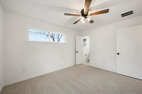 an empty room with a window and a fan