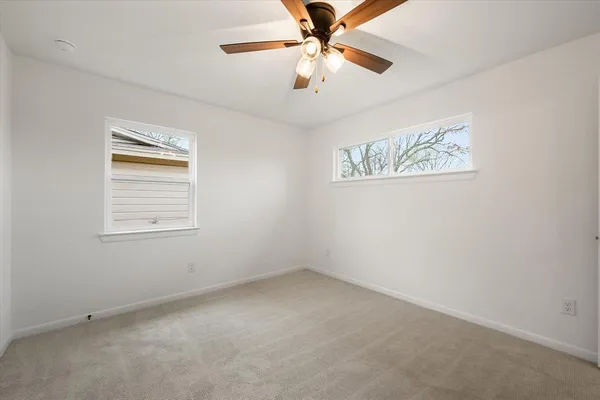 an empty room with a window and a fan