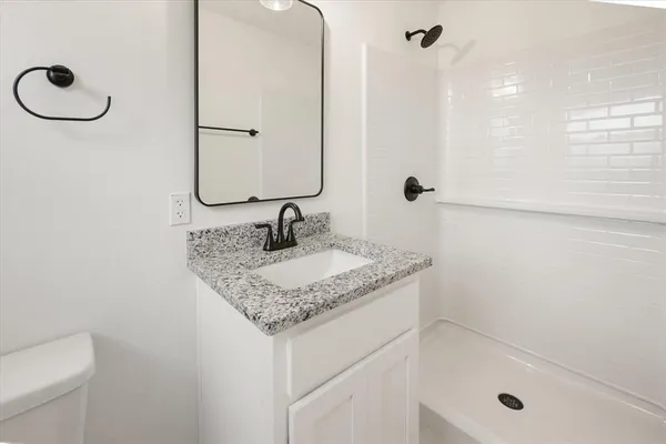 a bathroom with a granite countertop sink a toilet and shower