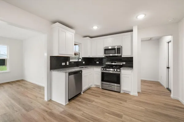 a kitchen with granite countertop a stove top oven and cabinets