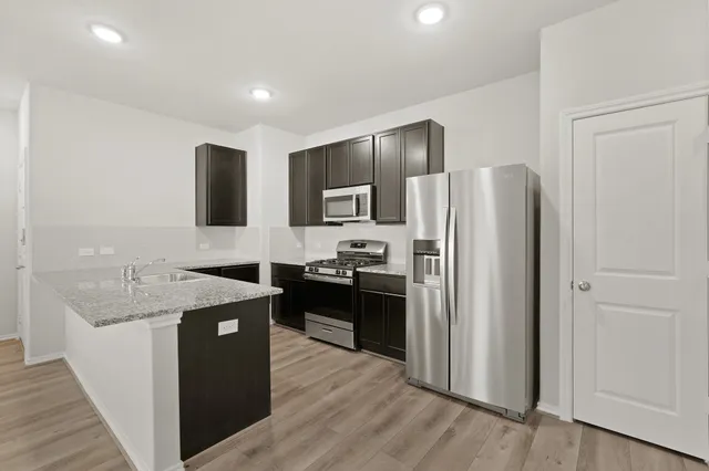 a kitchen with stainless steel appliances granite countertop a refrigerator a sink a stove and oven