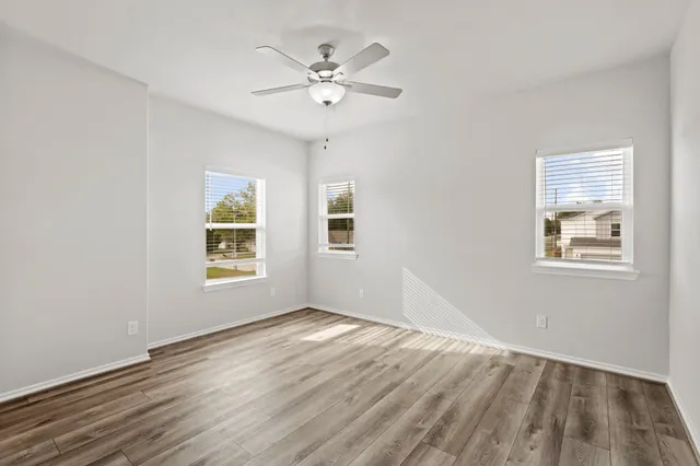 a view of an empty room with wooden floor and a window