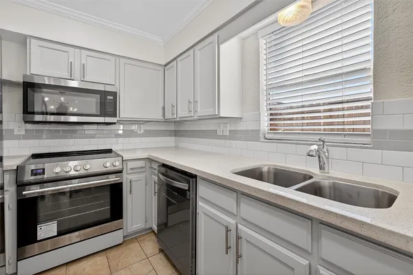 a kitchen with white cabinets a sink and stainless steel appliances