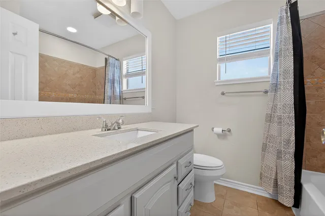 a bathroom with a granite countertop sink a toilet and a mirror
