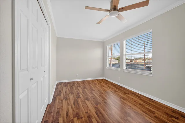 a view of a room with wooden floor ceiling fan and windows