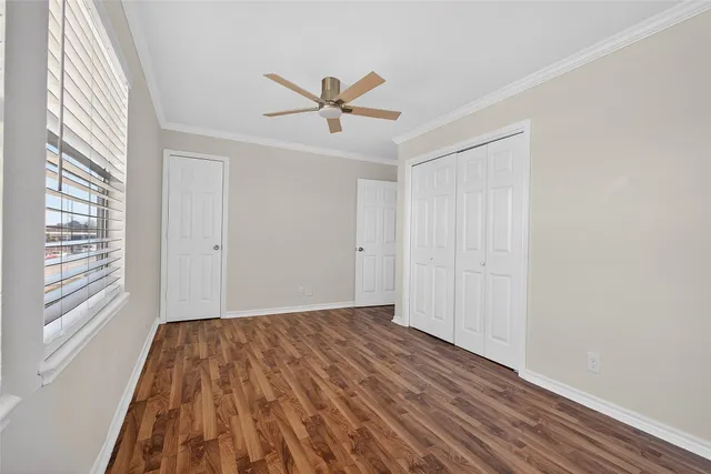 a view of empty room with wooden floor and fan