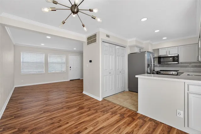 a view of an empty room with window and wooden floor