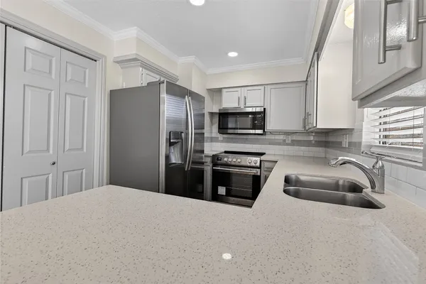 a kitchen with granite countertop a refrigerator a sink a stove a microwave and wooden cabinets