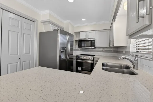 a kitchen with granite countertop a refrigerator a sink a stove a microwave and wooden cabinets