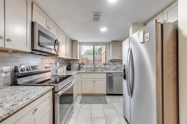 a kitchen with stainless steel appliances granite countertop a refrigerator sink and stove