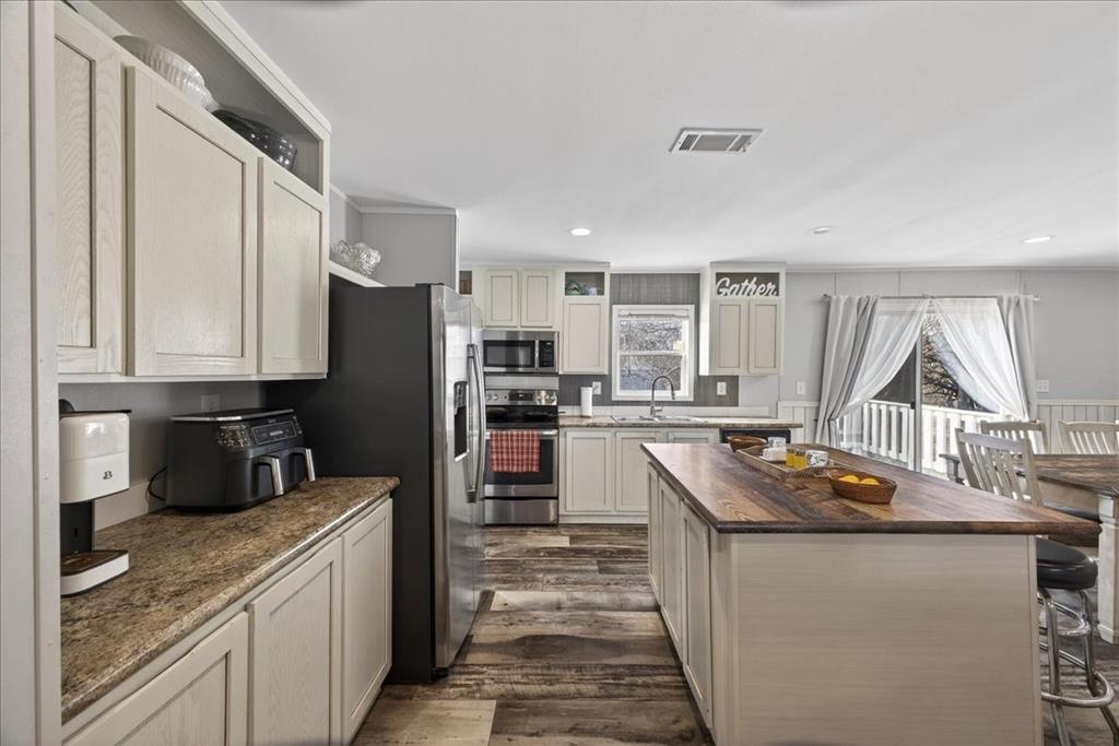 3605 Mockingbird Circle Cleburne, TX 76031 - Photo 15 of 40 Kitchen with stainless steel appliances, dark wood finished floors, a center island, a breakfast bar area, and butcher block counters