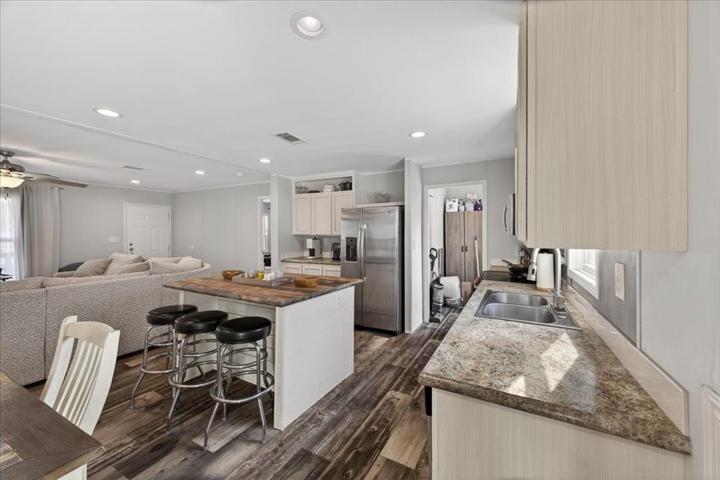 3605 Mockingbird Circle Cleburne, TX 76031 - Photo 16 of 40 Kitchen featuring stainless steel appliances, a breakfast bar, a center island, dark wood-style flooring, and ornamental molding