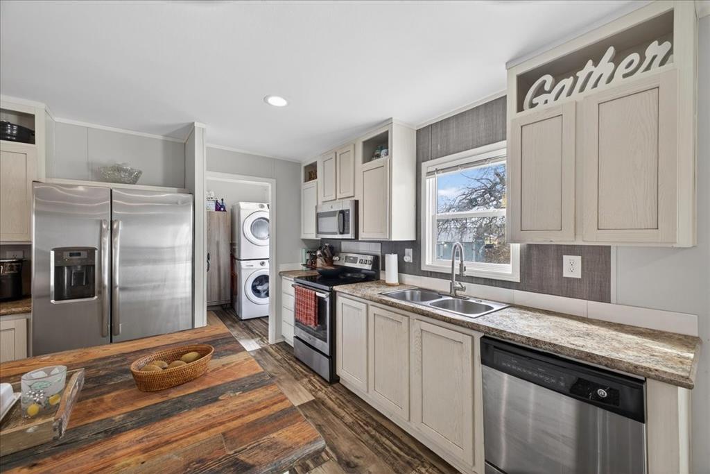 3605 Mockingbird Circle Cleburne, TX 76031 - Photo 17 of 40 Kitchen featuring stainless steel appliances, stacked washer / dryer, glass insert cabinets, recessed lighting, and dark wood-style floors