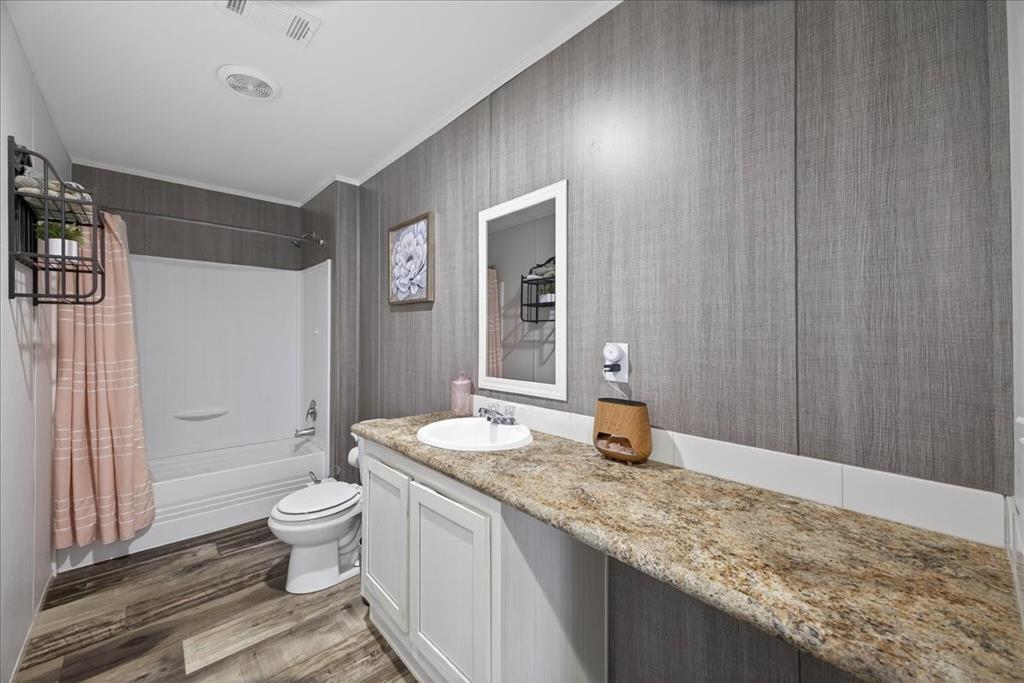 3605 Mockingbird Circle Cleburne, TX 76031 - Photo 32 of 40 Full bath featuring vanity, shower / tub combo with curtain, wallpapered walls, dark wood finished floors, and ornamental molding