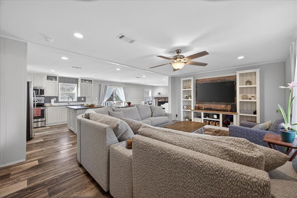 3605 Mockingbird Circle Cleburne, TX 76031 - Photo 9 of 40 Living area featuring dark wood-style flooring, recessed lighting, a fireplace, a ceiling fan, and built in shelves