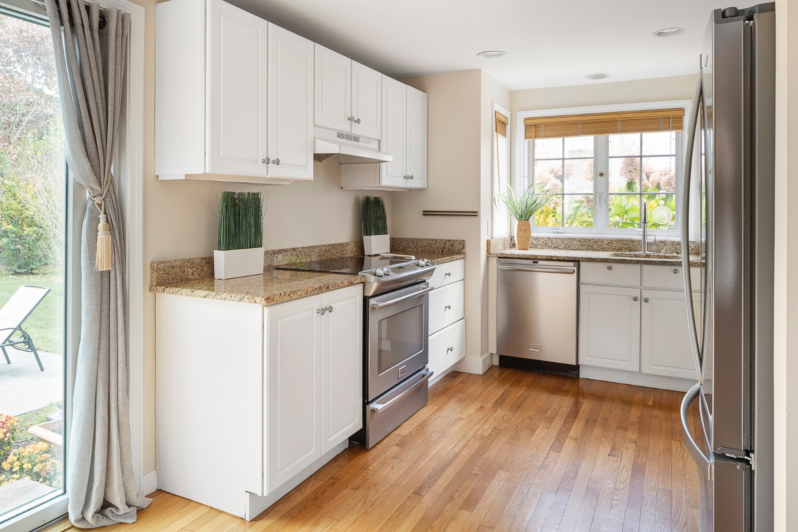 87 Schoolhouse Road Edgartown, MA 02539 - Photo 8 of 29 a kitchen with stainless steel appliances granite countertop a stove a sink and white cabinets with wooden floor