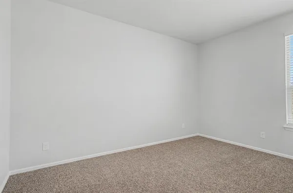 a view of an empty room with closet and a window